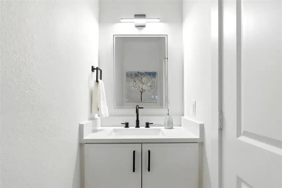 Half bath downstairs includes a quartz vanity, illuminated mirror, and modern lighting. Half bath downstairs includes a quartz vanity, illuminated mirror, and modern lighting.