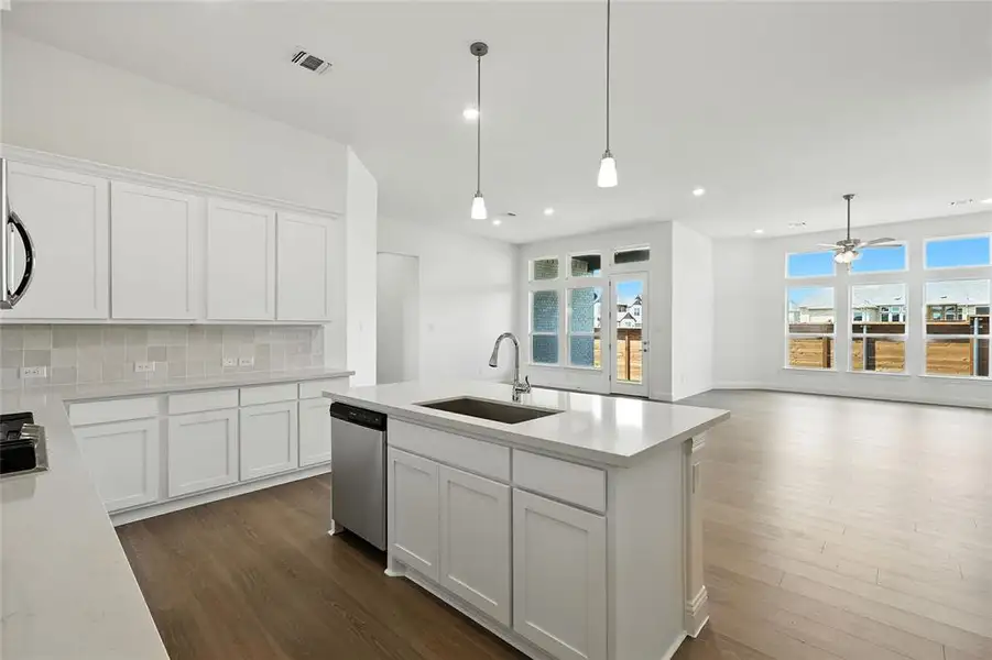 Kitchen with white cabinets, decorative light fixtures, dark wood-style flooring, and recessed lighting