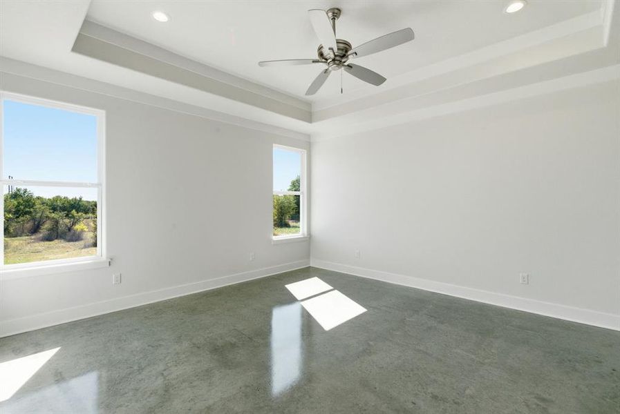 Unfurnished room featuring a raised ceiling, concrete flooring, recessed lighting, and a ceiling fan