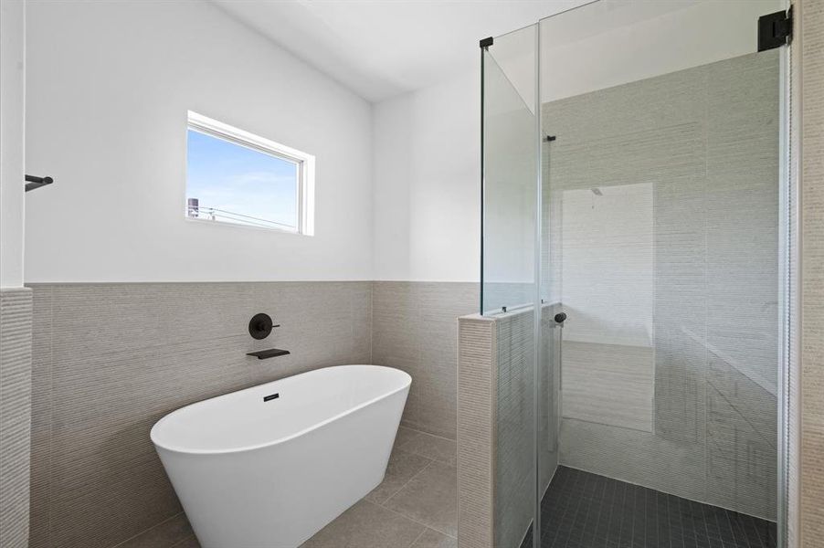 Luxurious freestanding soaking tub and glass enclosed walk-in shower.