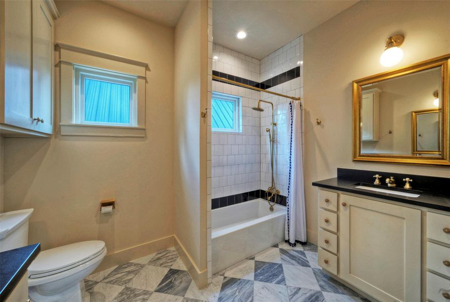 Marble tile flooring and gold fixtures elevate this bathroom's sophisticated aesthetic.