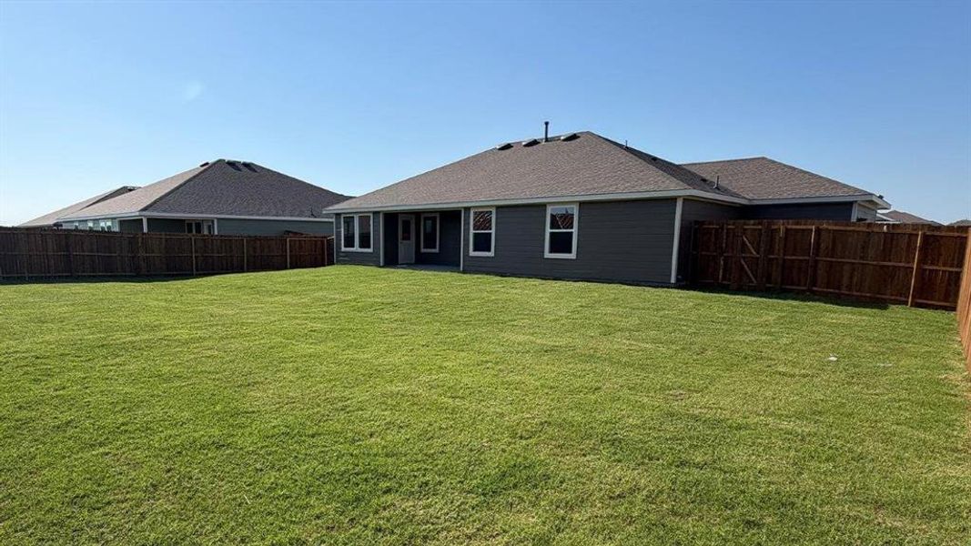 Expansive backyard featuring a lush lawn, privacy fencing, and a siding exterior
