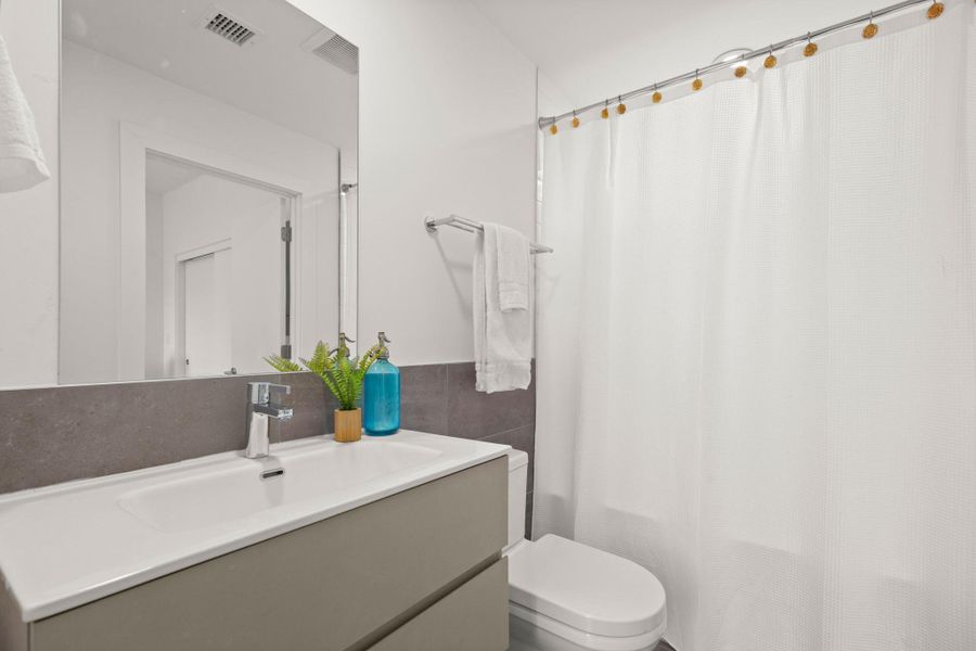 Bathroom featuring a white integrated sink, gray vanity, chrome faucet, and full-width mirror