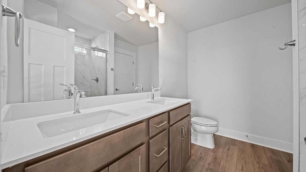 Superior en-suite primary bathroom with stylish dual vanity and tiled walk-in shower crafted with high standards in mind