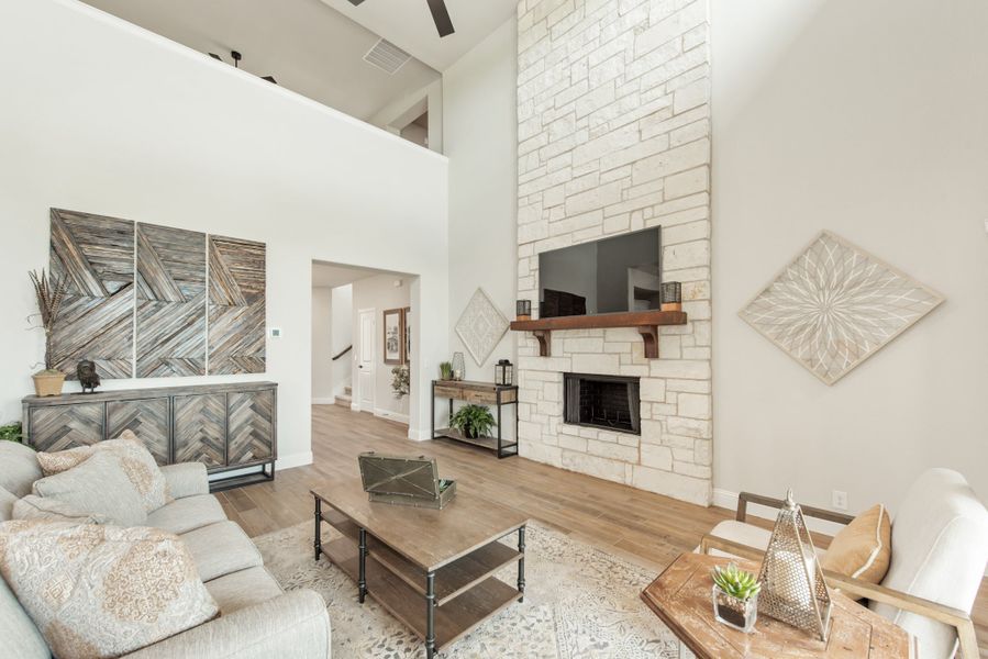 Living room with two-story stone fireplace, wood mantel, hardwood floors, and neutral seating area