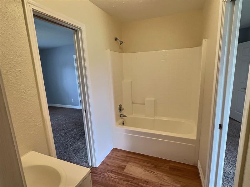 Full bath featuring dark wood finished floors, vanity, and shower / tub combination