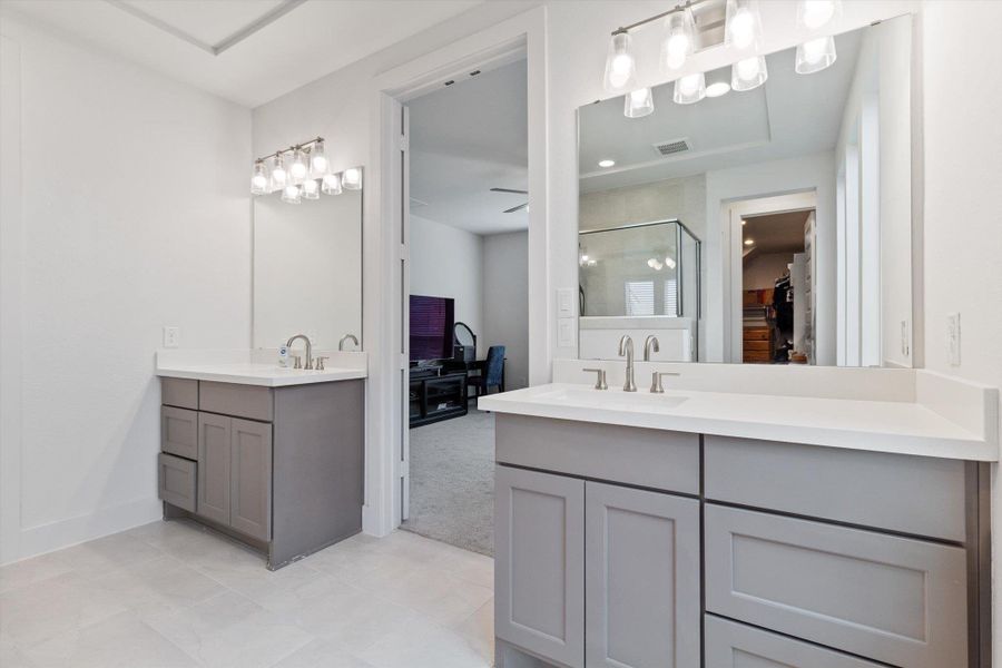 Full bathroom featuring a spacious closet, two vanities, a shower stall, and light colored carpet