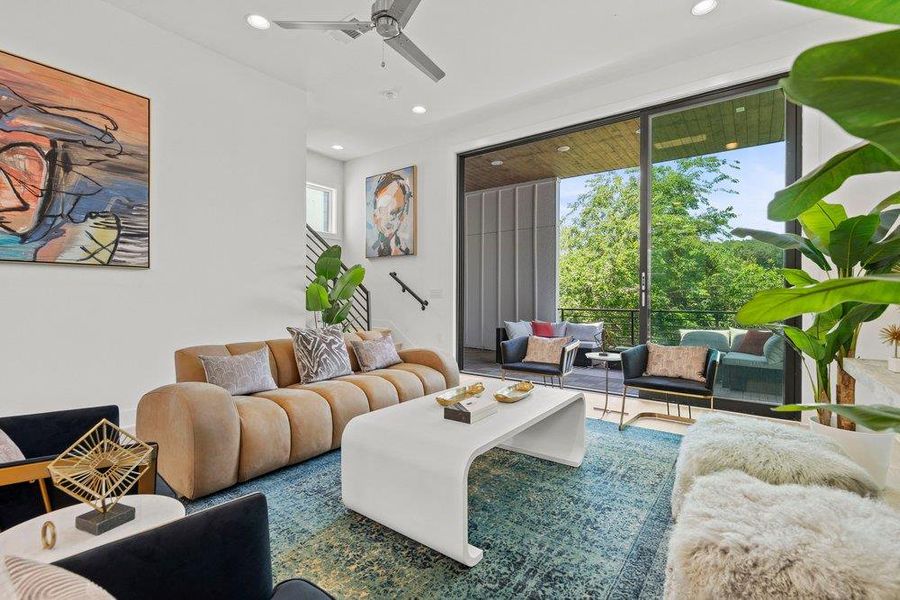 Sophisticated living area featuring oversized sliding glass doors and abundant natural light overlooking lush view from the balcony.