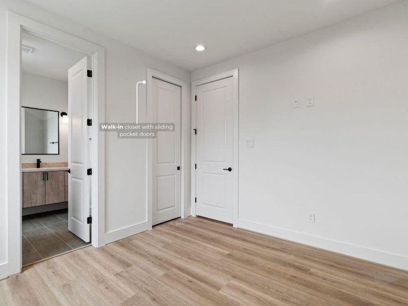 This guest bedroom includes a walk-in closet and private ensuite bath, complete with modern sconce lighting.