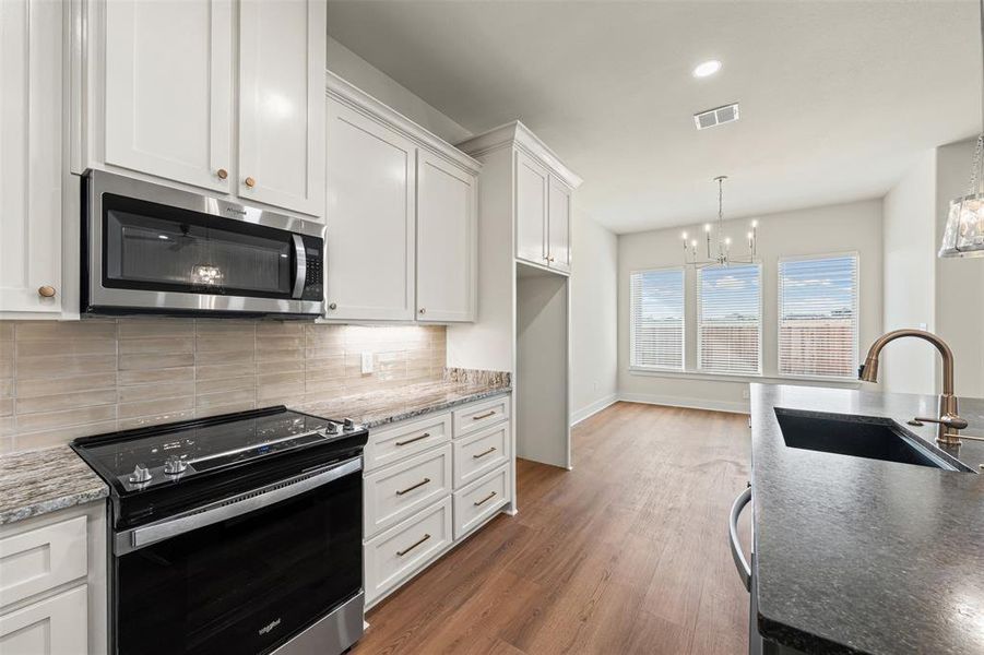 Kitchen featuring appliances with stainless steel finishes, white cabinets, dark wood-style floors, dark stone counters, and recessed lighting