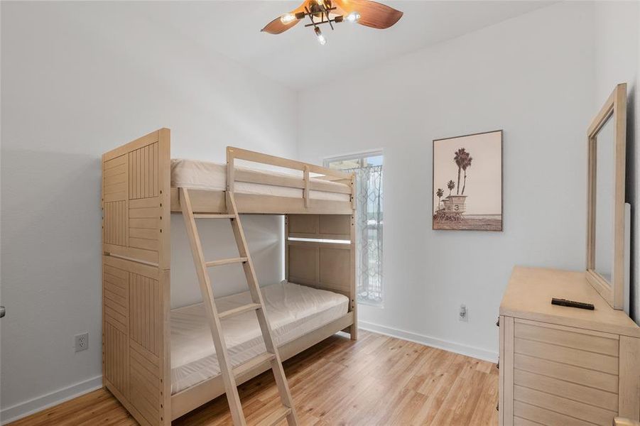 This is a bright, cozy secondary bedroom with a  ceiling fan and a window.