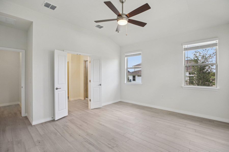 Unfurnished bedroom featuring vaulted ceiling, light wood-style floors, and ceiling fan