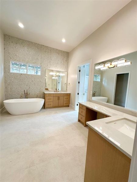 Oversized spa like bath with dual vanities with quartzite countertops, large mirror and elegant lighting. Large soaking tub, spacious shower, and a large closet with custom built ins.