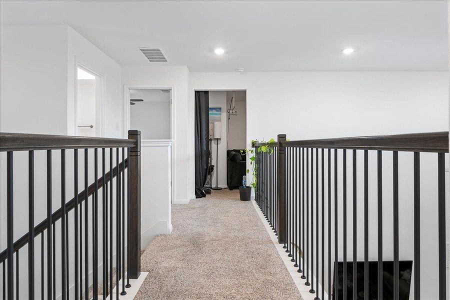Hallway featuring light carpet, an upstairs landing, and recessed lighting