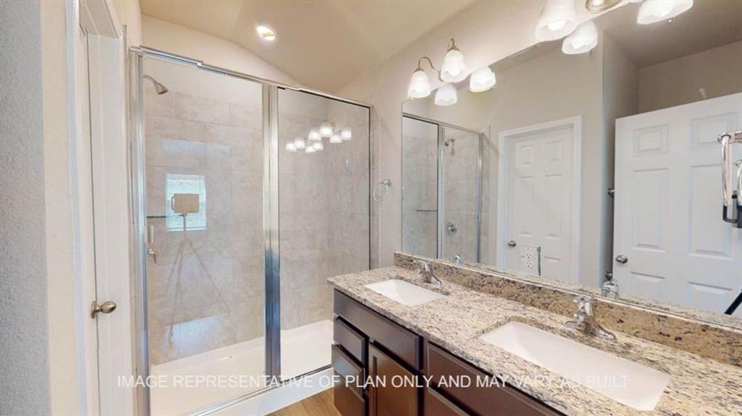 Bathroom featuring a stall shower, double vanity, and lofted ceiling Bathroom featuring a stall shower, double vanity, and lofted ceiling