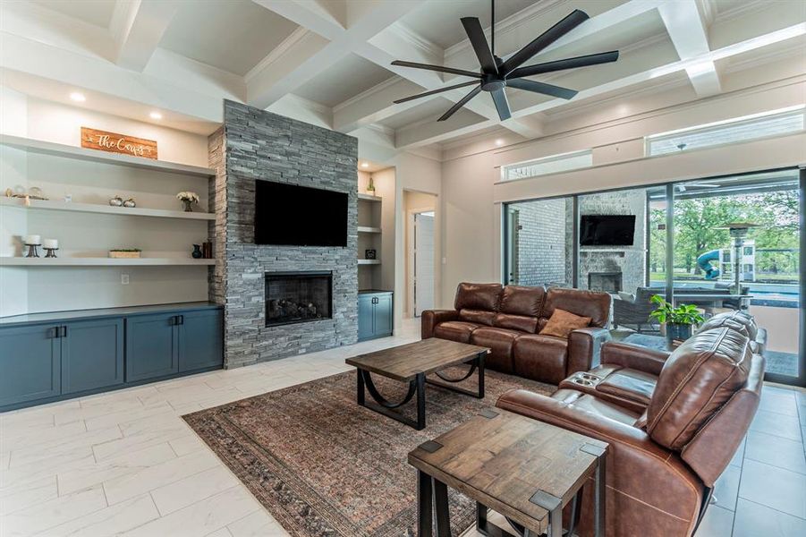 Living area with a fireplace, ceiling fan, built in features, coffered ceiling, and light marble finish floors Living area with a fireplace, ceiling fan, built in features, coffered ceiling, and light marble finish floors