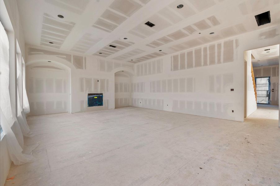 Spacious living area with 11-foot ceilings, two beautiful arches, and planned white oak cabinetry with floating shelves.