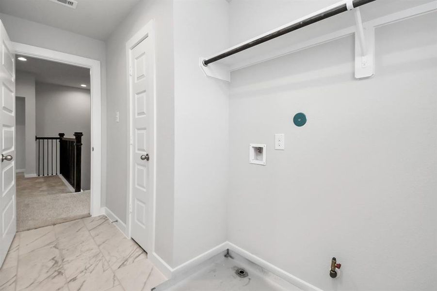 A spacious utility room with ample shelving for organization. It features connections for both gas and electric dryers, making it versatile and functional for all laundry needs. Sample photo of completed home with similar floor plan. Actual colors and selections may vary.