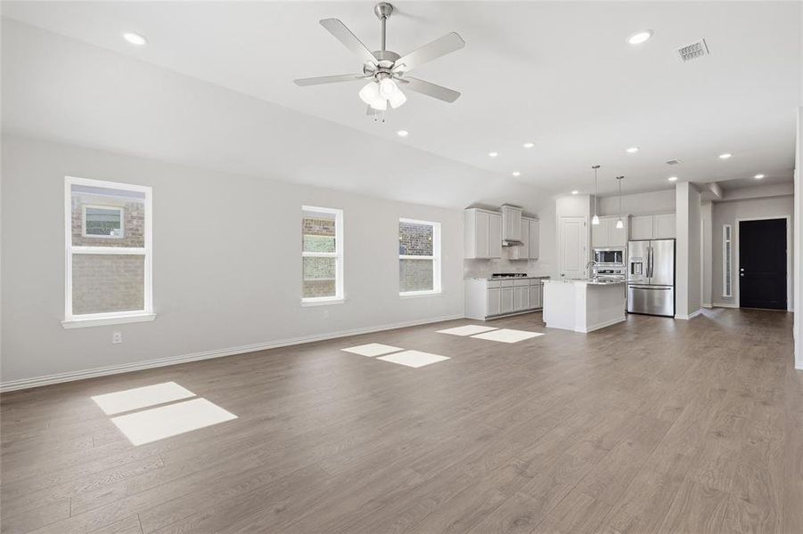 Unfurnished living room with ceiling fan, light wood finished floors, and recessed lighting Unfurnished living room with ceiling fan, light wood finished floors, and recessed lighting