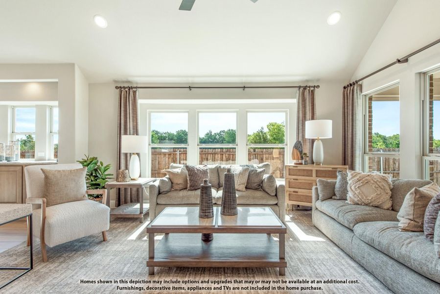 Bright living room with vaulted ceiling, gray sofas, wood coffee table, and large windows with natural light.