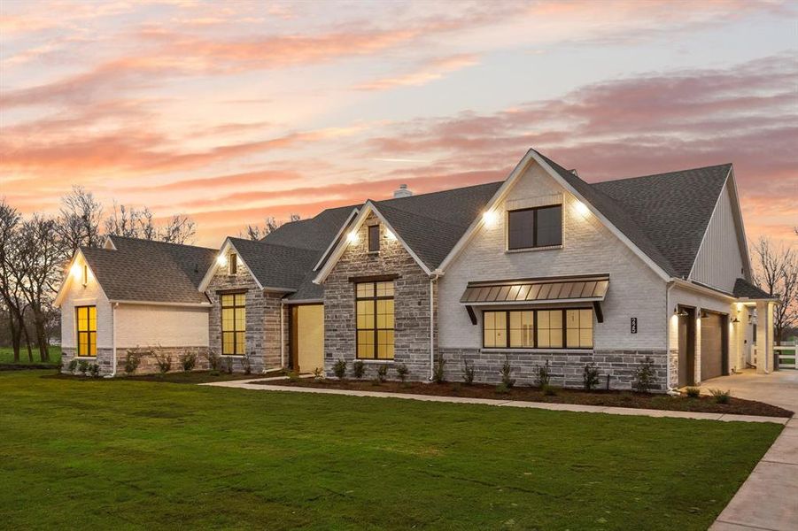 Modern farmhouse with a lawn, stone siding, concrete driveway, and a garage