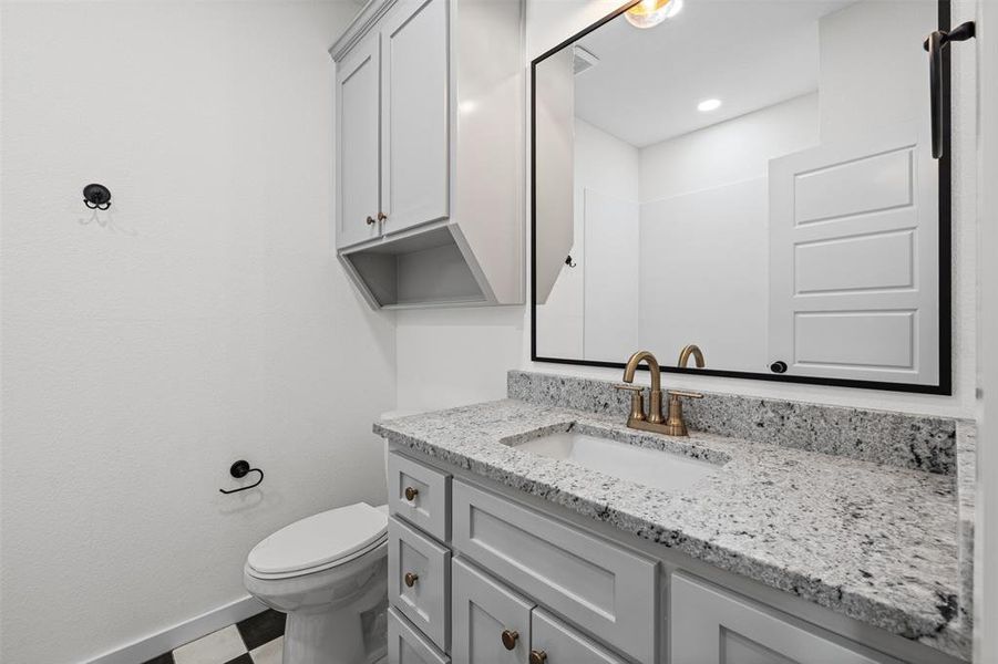 The bathroom features a modern vanity with a white countertop and an integrated sink, complemented by light gray cabinetry with brass-toned hardware