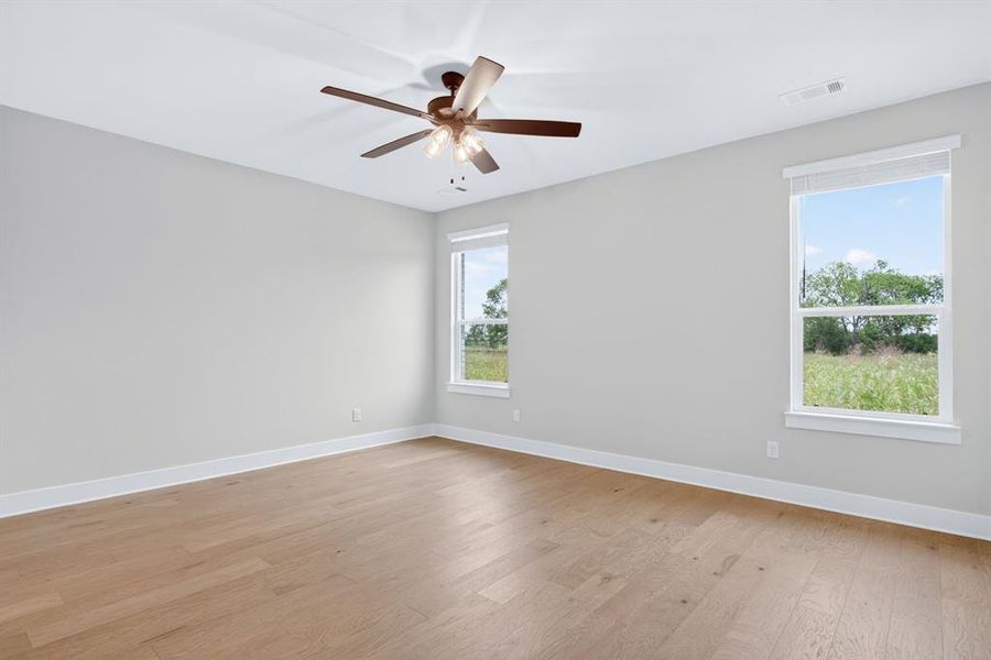 Spacious room featuring wood-finish flooring, light gray walls, and white trim Spacious room featuring wood-finish flooring, light gray walls, and white trim