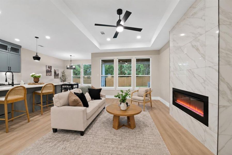 Spacious living area featuring light wood-finish flooring and a contemporary fireplace with a large-format tiled surround Spacious living area featuring light wood-finish flooring and a contemporary fireplace with a large-format tiled surround