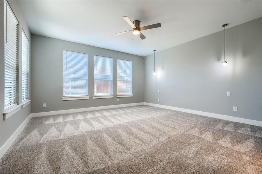 Carpeted empty room featuring ceiling fan and plenty of natural light