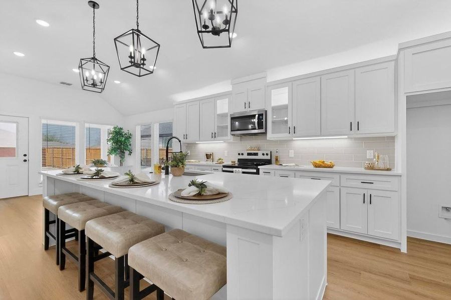 Kitchen with white cabinetry, a kitchen breakfast bar, light wood-type flooring, vaulted ceiling, and electric range oven Kitchen with white cabinetry, a kitchen breakfast bar, light wood-type flooring, vaulted ceiling, and electric range oven