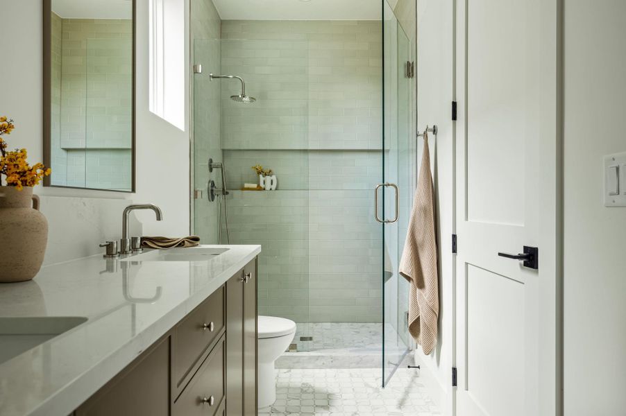 A refined bathroom featuring dual sinks and a contemporary walk-in shower with clear glass.
