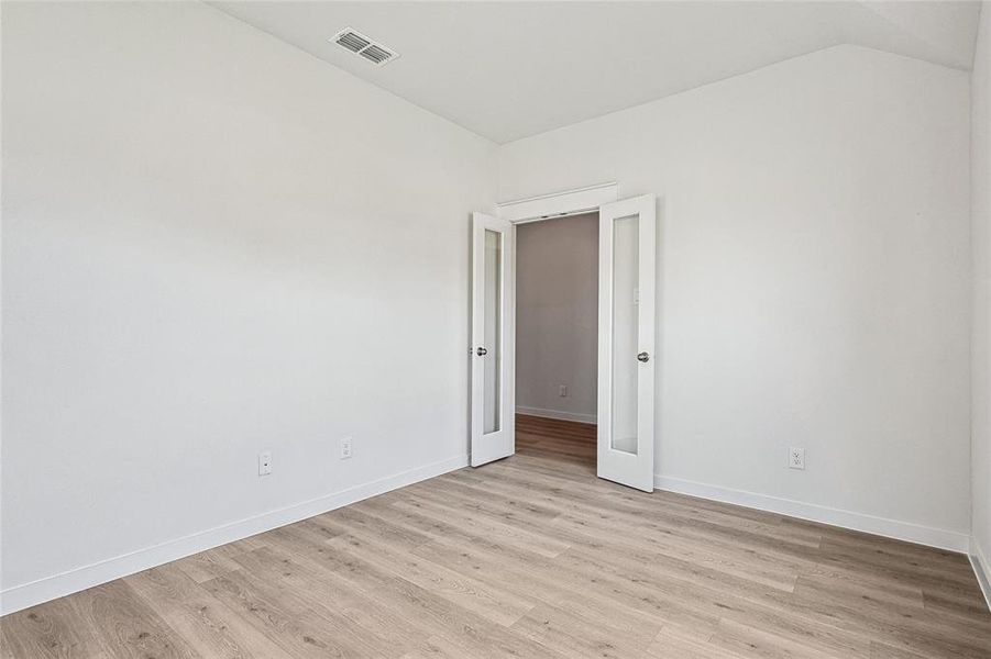 Unfurnished room with lofted ceiling and light hardwood / wood-style floors