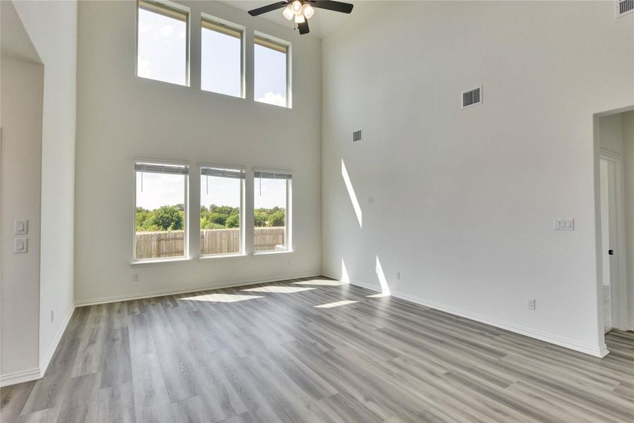 Unfurnished living room with a towering ceiling, light wood finished floors, and ceiling fan