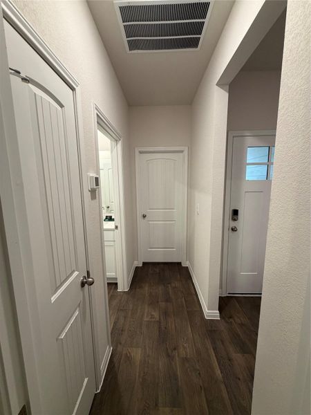 Corridor featuring dark wood finished floors and a textured wall