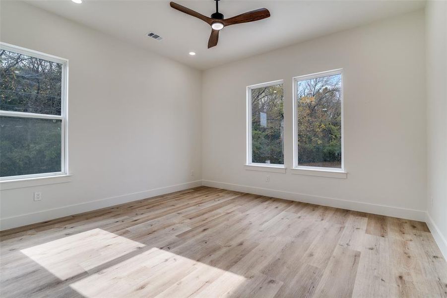Spare room featuring light wood finished floors, ceiling fan, plenty of natural light, and recessed lighting