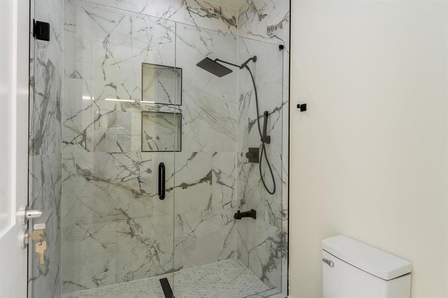 Full bathroom featuring a marble finish shower and toilet