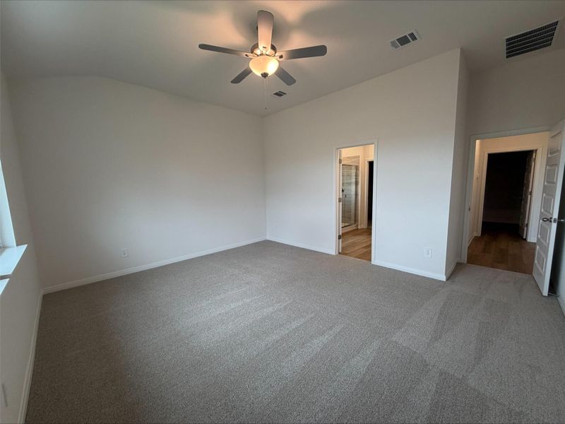 Unfurnished bedroom with ceiling fan, light carpet, and connected bathroom Unfurnished bedroom with ceiling fan, light carpet, and connected bathroom