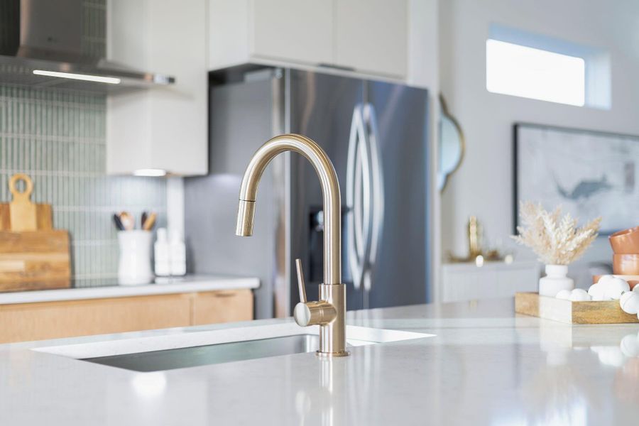 Kitchen view of decorative backsplash, light stone countertops, white cabinetry, and modern cabinets