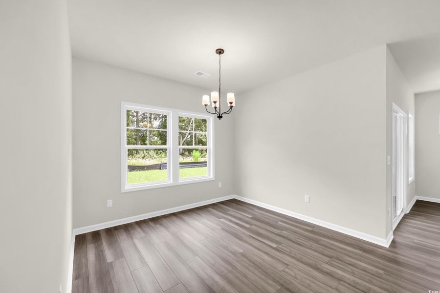 Unfurnished dining area with light wood finished floors and a chandelier