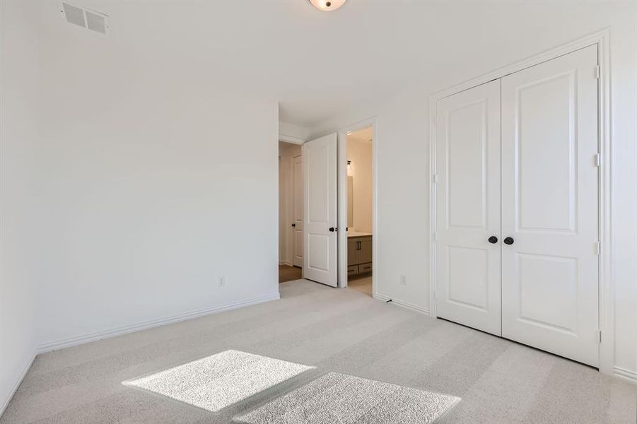 Carpeted bedroom featuring a closet and connected bathroom