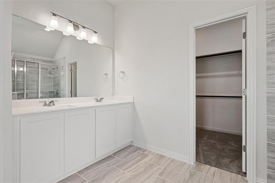 Bathroom featuring double vanity, an enclosed shower, tile flooring, and lofted ceiling