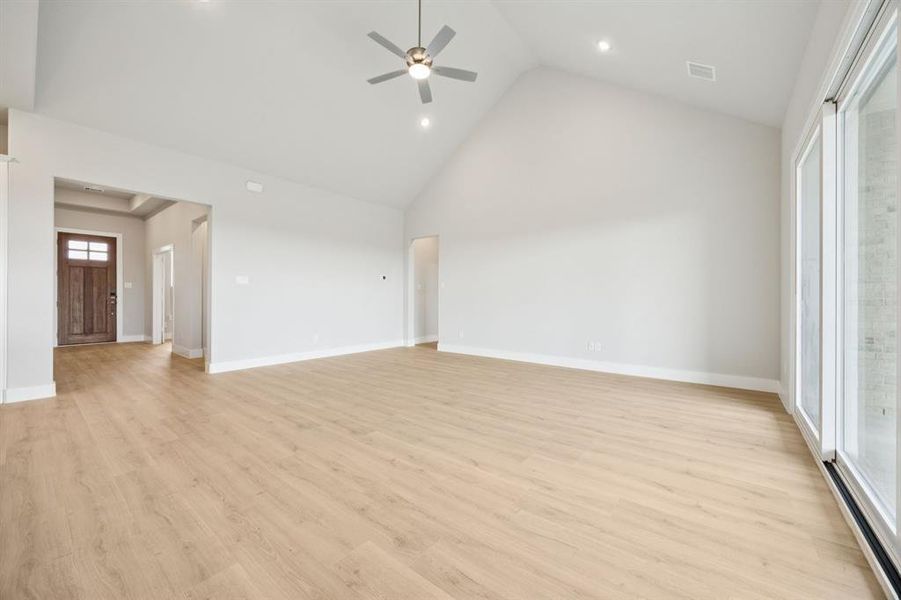 Unfurnished living room with high vaulted ceiling, light wood finished floors, ceiling fan, and recessed lighting