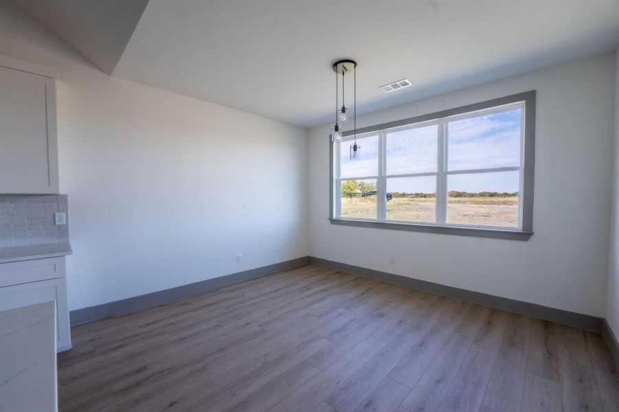 Unfurnished dining area featuring light wood-style flooring and baseboards Unfurnished dining area featuring light wood-style flooring and baseboards