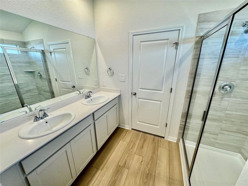 Full bath featuring a shower stall, light wood-style flooring, and double vanity Full bath featuring a shower stall, light wood-style flooring, and double vanity
