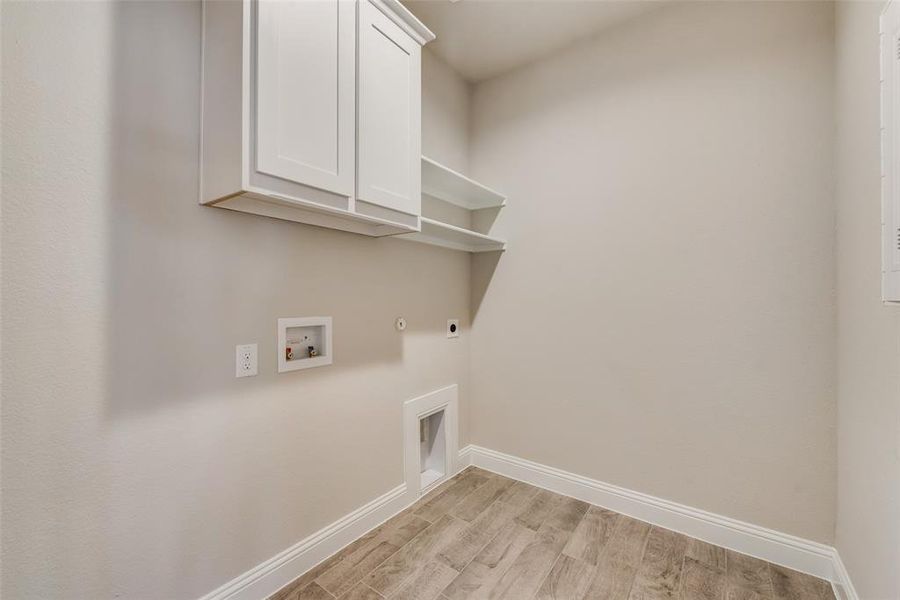 Washroom featuring cabinets, light hardwood / wood-style flooring, hookup for a washing machine, hookup for an electric dryer