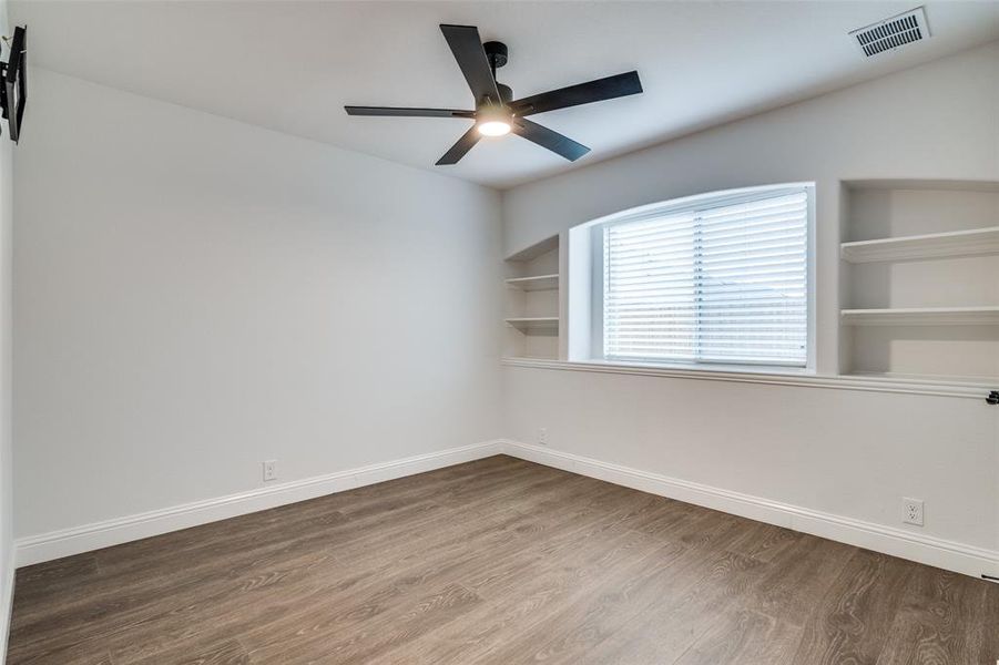 Bedroom with a barn door, ceiling fan, built in features, and wood-type flooring