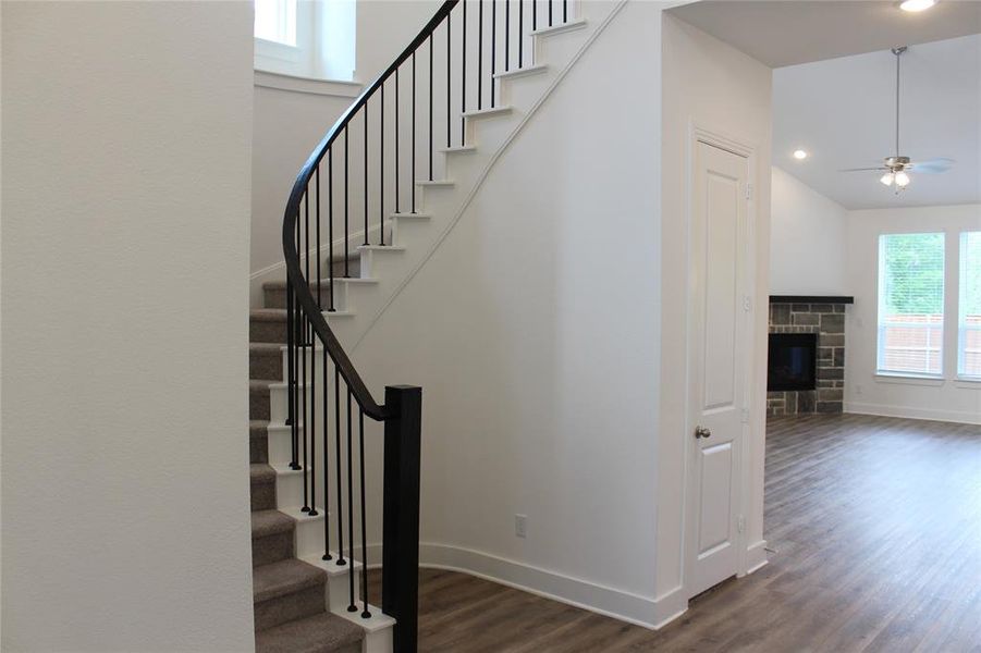Stairs with wood finished floors, a fireplace, ceiling fan, and recessed lighting