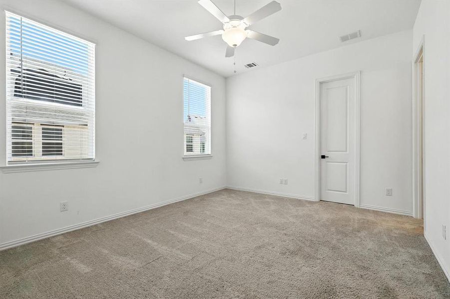Walk down from the kitchen into the spacious primary. Large windows, and ceiling fan too.