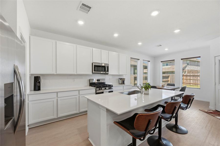Modern kitchen with large island, breakfast bar seating, and quartz countertops.