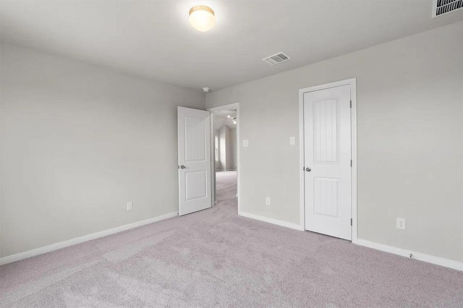 A spacious, naturally illuminated room features plush carpeting and white trim.